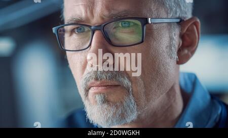 Nahaufnahme Porträt des gutaussehenden Mann mittleren Alters trägt eine Brille, die am Computer arbeitet. Attraktiver grauhaariger Mann mit blauen Augen Stockfoto