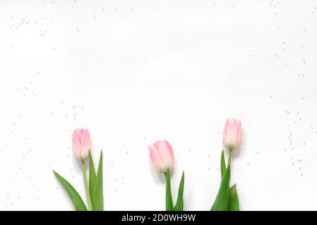 Flach legen mit rosa Tulpen und rosa Konfetti auf weißem Hintergrund und Kopierraum. Muttertag Stockfoto