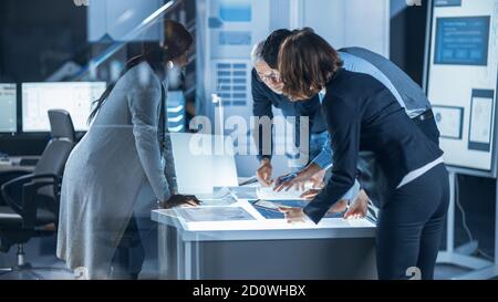 Ingenieure treffen in Technology Research Laboratory: Ingenieure, Wissenschaftler und Entwickler versammelten sich um beleuchteten Konferenztisch, reden und Stockfoto