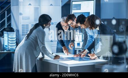 Ingenieure treffen in Technology Research Laboratory: Ingenieure, Wissenschaftler und Entwickler versammelten sich um beleuchteten Konferenztisch, reden und Stockfoto