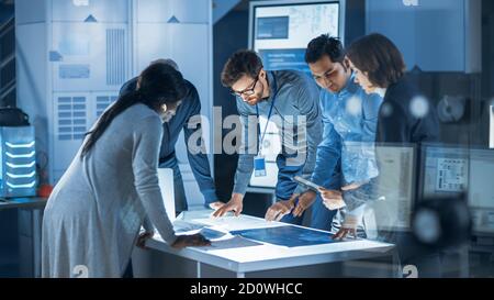 Ingenieure treffen in Technology Research Laboratory: Ingenieure, Wissenschaftler und Entwickler versammelten sich um beleuchteten Konferenztisch, reden und Stockfoto