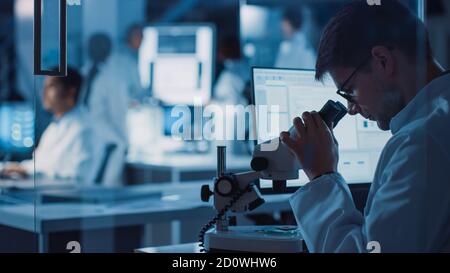 In Technology Research Laboratory: Diverse Team von Industriewissenschaftlern, Ingenieuren, Entwicklern versammeln sich um Leuchttisch und Inspect Blueprints Stockfoto