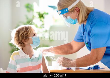 Coronavirus-Impfung. Covid-19-Impfstoff. Arzt, der Kind impft. Kinder in der Klinik. Kleiner Junge bekommt Grippeschutzimpfung. Kinderarzt untersucht Kind und Givin Stockfoto