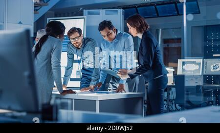 Ingenieure treffen in Technology Research Laboratory: Ingenieure, Wissenschaftler und Entwickler versammelten sich um beleuchteten Konferenztisch, reden und Stockfoto