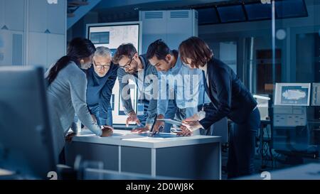 Ingenieure treffen in Technology Research Laboratory: Ingenieure, Wissenschaftler und Entwickler versammelten sich um beleuchteten Konferenztisch, reden und Stockfoto