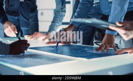 Ingenieur, Wissenschaftler und Entwickler versammelten sich um beleuchtete Konferenztisch im Technology Research Center, sprechen, Lösung finden und Stockfoto