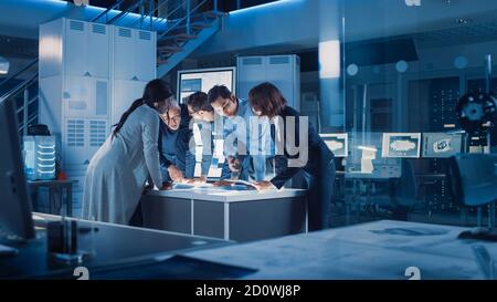 Ingenieure treffen in Technology Research Laboratory: Ingenieure, Wissenschaftler und Entwickler versammelten sich um beleuchteten Konferenztisch, reden und Stockfoto