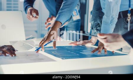Ingenieur, Wissenschaftler und Entwickler versammelten sich um beleuchtete Konferenztisch im Technology Research Center, sprechen, Lösung finden und Stockfoto