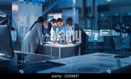 Ingenieure treffen in Technology Research Laboratory: Ingenieure, Wissenschaftler und Entwickler versammelten sich um beleuchteten Konferenztisch, reden und Stockfoto