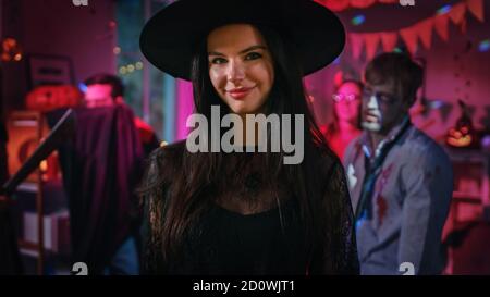 Halloween Kostüm Party: Wunderschöne junge Hexe trägt Kleid und Hut posiert verführerisch. Hintergrund: Schöner She Devil, Scary Death, Graf Dracula Stockfoto