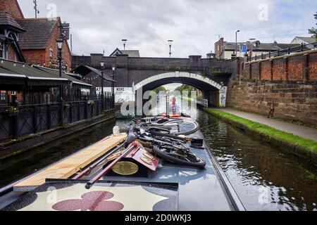 Eine Frau steuert ein Schmalboot unter einer Brücke auf dem Bridgewater Canal in Sale, Manchester Stockfoto