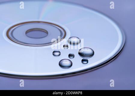 CD mit Wassertröpfchen darauf - Nahaufnahme mit selektivem Fokus, futuristisch bunten Hintergrund und Textur-Idee Stockfoto