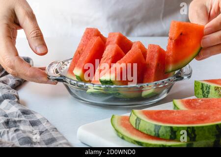 Frische reife Wassermelone Scheiben auf einem Teller und Schneidebrett. Frau serviert Obstsalat Stockfoto