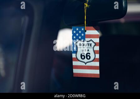 Route 66-Symbol oder -Logo am Rückspiegel In einem Auto mit amerikanischer Flagge auf dem Hintergrund Stockfoto