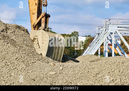 Baggerarbeiten - Baggereimer auf einem Haufen ausgegrabener Erde Vor einer Eisenbahnbrücke über den Fluss Stockfoto