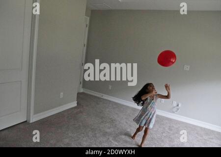 Fünf Jahre altes Mädchen spielt mit einem roten Ballon in Ein leerer Raum Stockfoto