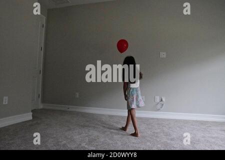 Fünf Jahre altes Mädchen spielt mit einem roten Ballon in Ein leerer Raum Stockfoto