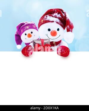 Zwei kleine Schneemänner das Mädchen und der Junge in Mützen und Schals auf Schnee im Winter. Festliche Hintergrund mit einem lustigen Schneemann. Weihnachtskarte, kopieren. Stockfoto