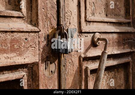 Das Schloss an der alten Holztür schloss sich. Rost auf dem Metallschloss. Die braune Farbe blättert an der alten Tür ab. Uralte Textur. Stockfoto