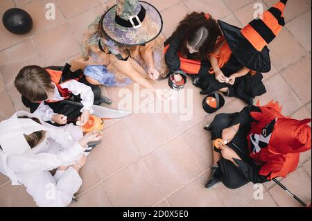 Kinder, die auf dem Boden sitzen und ihre Süßigkeiten vergleichen Halloween Stockfoto