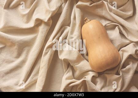 Goldener Kürbis auf Leinenhintergrund für dekorative Gestaltung. Grußkartenvorlage. Ernte und Danksagung. Stillleben Minimalismus. Stockfoto