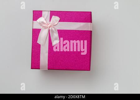 Isolierte kleine rosa Geschenk-Box, geschlossen hell lila Urlaub Geschenk-Box mit einer rosa Spitze Schleife auf der Oberseite liegt auf einem weißen Hintergrund Stockfoto