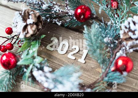 Komposition zum neuen Jahr. Weihnachtskranz mit Tannenzweigen Dekorationen auf altem dunklen Holzhintergrund mit 2021 Buchstaben Text, flaches Lay, Seitenansicht Stockfoto