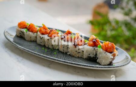 Lachs-Tartarrollen in weißem Teller mit Kaviar und Soja Sauce auf weißem Hintergrund vor dem Restaurant Stockfoto