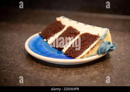 Eine reichhaltige, feuchte Schokoladencreme, dreilagige Torte mit dicker Vanillevereisung und graublau gefärbten Buttercreme-Rosetten. Stockfoto