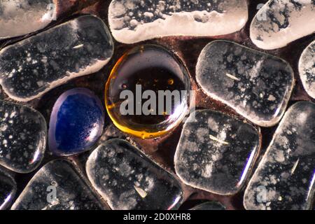 Schöne Lichtreflexion auf einem orangefarbenen Glasstein und andere Steine Stockfoto