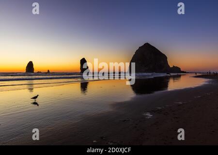 Dramatischer Sonnenuntergang am Strand mit Haystack Rock und The Nadeln Stockfoto