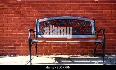 Rote Ziegelwand Mit Blumenmuster Und Gusseisen-Bank Stockfoto