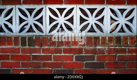 Rote Ziegelwand mit floralen Betonblöcken Stockfoto