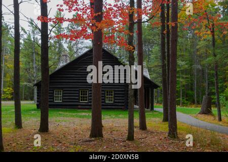 Blockhütte Im Wald. Traditionelle Blockhütte in einem abgelegenen Wald, eingerahmt von Herbstlaub. Dies ist ein historisches Gebäude in einem State Park Stockfoto