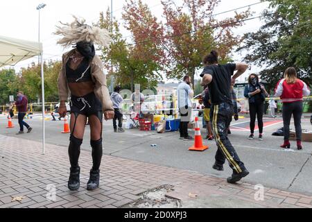 Seattle, Washington, USA. Oktober 2020. Ein Nachtschwärmer, der den Namen Queen B trägt, tanzt zu DJ's Musik als Künstler aus der Vivid Matter Kollektivarbeit, um das Wandgemälde Black Lives Matter im Viertel Capitol Hill in Seattle wiederherzustellen. Das Kollektiv von schwarzen und indigenen Künstlern schuf das ursprüngliche Wandbild während des Capitol Hill-Protestes im Juni. Sie arbeiteten mit dem Büro für Kunst und Kultur der Stadt Seattle zusammen, um das Wandbild zu restaurieren und es zu einem dauerhaften Wahrzeichen zu machen. Quelle: Paul Christian Gordon/Alamy Live News Stockfoto