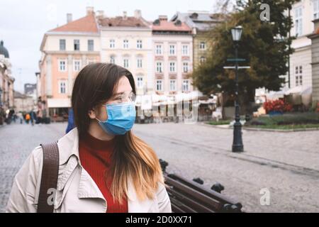 Schöne junge Frau, trägt Einweg-Schutz Gesichtsmaske zu Fuß die Straße. Pandemieprävention und neues normales Konzept. Luftverschmutzung und Stockfoto
