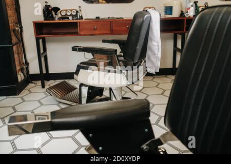 Verstellbare Stühle in einem Friseurladen mit sechseckigem Muster Boden Stockfoto