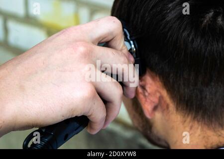 Der Barbier schneidet den Kerl mit einem Haarschneider ab Stockfoto