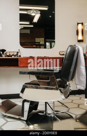 Bequemer Kosmetikstuhl in einem Friseurladen auf hexagonalem gemustertem Boden Stockfoto