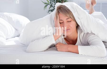 Schöne junge Frau im weißen Bett am Morgen, will nicht aufwachen. Nicht genug Schlaf. Stockfoto