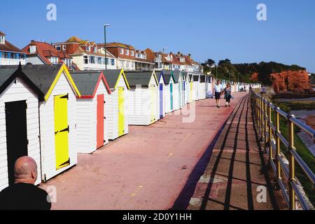 Paignton, Devon, Großbritannien. September 18, 2020. Urlauber, die auf der Promenade vor bunten Strandhütten am Preston Sands in Paignton in devon spazieren. Stockfoto