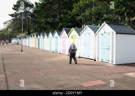 Goodrngton, Devon, Großbritannien. September 18, 2020. Urlauber, die auf der Promenade vor bunten Strandhütten in Goodrington bei Paignton in Devon, Großbritannien, spazieren gehen Stockfoto