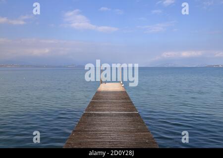 Seebrücke Am Gardasee. Der Blick entlang einer hölzernen Pier am Ufer des Gardasees in Nordostitalien. Stockfoto