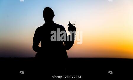 Dubai, VAE - Juni 2013: Falcon Trainer Silhouette in der Wüste mit Sonnenuntergang Landschaft Stockfoto