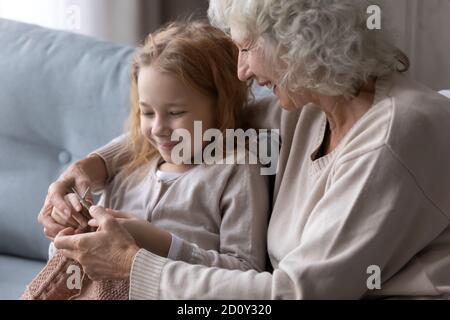 Nahaufnahme liebevolle reife Großmutter, die kleine Enkelin zum Stricken beibringt Stockfoto