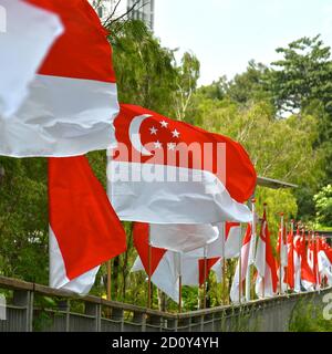 Eine perspektivische Ansicht einer Reihe von Flaggen Singapurs, die im Wind flattern. Sie werden jedes Jahr zur Vorbereitung auf die Feierlichkeiten zum Nationalfeiertag ausgestellt. Stockfoto