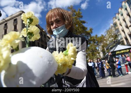Barcelona, Spanien. Oktober 2020. Eine Frau, die eine Gesichtsmask trägt, bereitet während der Feier des Festivals Roser de La Rambla einen Blumenstrauß vor.das Festival Roser findet seit 1962 jedes Jahr ohne weiteres statt. Nachbarn dieses Viertels im Zentrum von Barcelona schmücken Straßen und Gebäude mit Blumen zu Ehren der Jungfrau vom Rosenkranz, schutzpatronin der berühmten Straße La Rambla. Kredit: SOPA Images Limited/Alamy Live Nachrichten Stockfoto