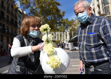 Barcelona, Spanien. Oktober 2020. Eine Frau trägt eine Gesichtsmask zeigt einem Mann, wie man Blumensträuße während der Feier des Roser de La Rambla Festival vorzubereiten.Roser Festival wird jedes Jahr ohne weiteres seit 1962 statt. Nachbarn dieses Viertels im Zentrum von Barcelona schmücken Straßen und Gebäude mit Blumen zu Ehren der Jungfrau vom Rosenkranz, schutzpatronin der berühmten Straße La Rambla. Kredit: SOPA Images Limited/Alamy Live Nachrichten Stockfoto