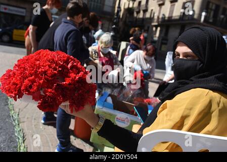 Barcelona, Spanien. Oktober 2020. Eine Frau mit Gesichtsmast posiert für ein Bild mit einem Blumenstrauß, den sie während der Feier des Festivals Roser de La Rambla gemacht hat.das Festival Roser findet seit 1962 jedes Jahr statt. Nachbarn dieses Viertels im Zentrum von Barcelona schmücken Straßen und Gebäude mit Blumen zu Ehren der Jungfrau vom Rosenkranz, schutzpatronin der berühmten Straße La Rambla. Kredit: SOPA Images Limited/Alamy Live Nachrichten Stockfoto