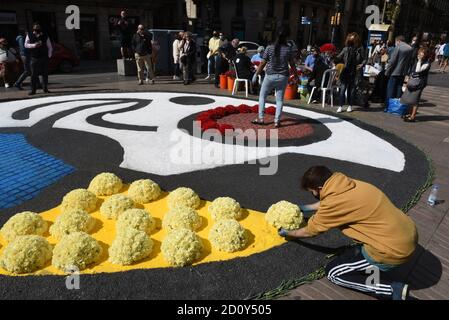 Barcelona, Spanien. Oktober 2020. Eine Person trägt eine Gesichtsmask platziert Blumensträuße von gelben Blumen auf dem Gorund während der Feier des Roser de La Rambla Festival.Roser Festival wird jedes Jahr ohne weiteres seit 1962 statt. Nachbarn dieses Viertels im Zentrum von Barcelona schmücken Straßen und Gebäude mit Blumen zu Ehren der Jungfrau vom Rosenkranz, schutzpatronin der berühmten Straße La Rambla. Kredit: SOPA Images Limited/Alamy Live Nachrichten Stockfoto